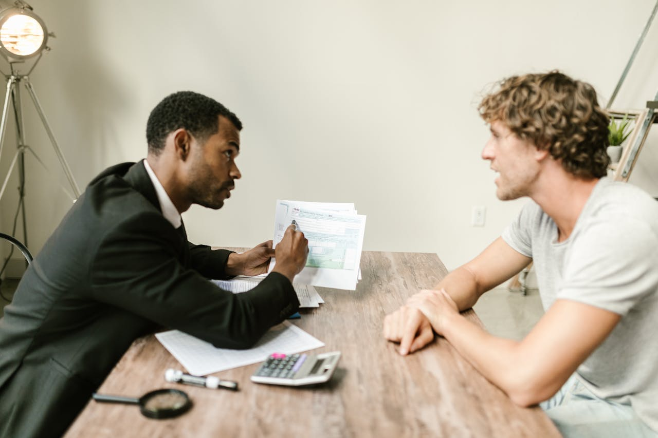 creative A financial advisor discusses paperwork with a client at a desk in a modern office.