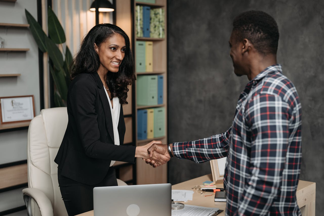 creative-02 Two professionals shake hands in a modern office, symbolizing a successful agreement.